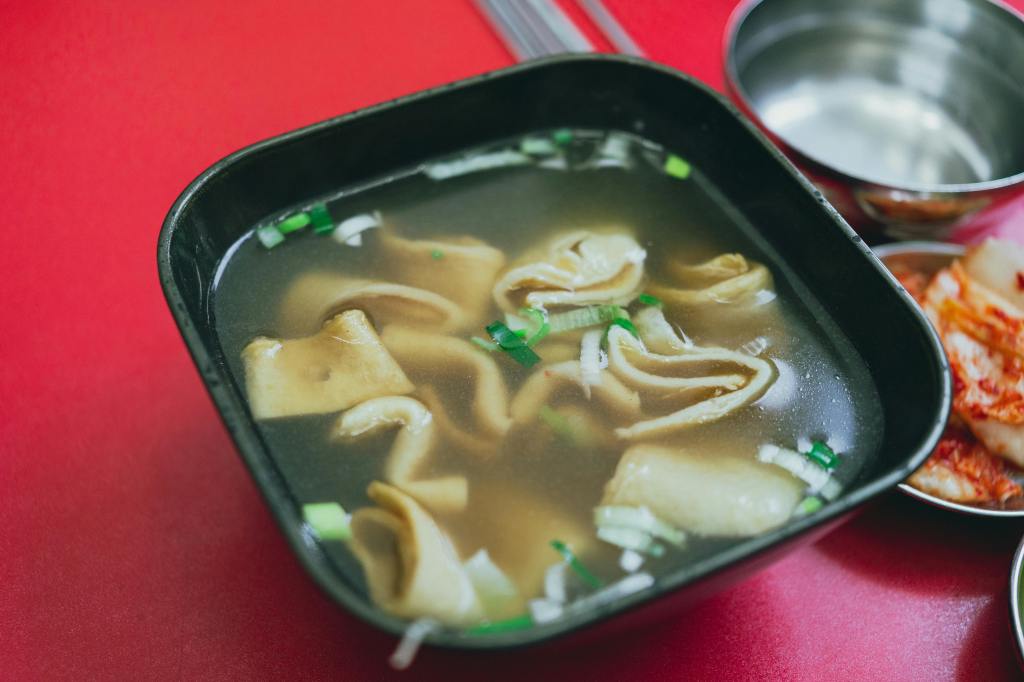 Skewered fish cakes (eomuk) soaking in a hot, savory broth at a street food stall.